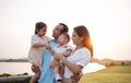 Happy family in the park sunset light. family on weekend playing together in the meadow with river Parents hold the child and Royalty Free Stock Photo