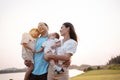 Happy family in the park sunset light. family on weekend playing together in the meadow with river Parents hold the child and Royalty Free Stock Photo