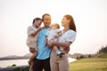 Happy family in the park sunset light. family on weekend playing together in the meadow with river Parents hold the child and Royalty Free Stock Photo