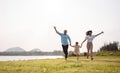 Happy family in the park sunset light. family on weekend running together in the meadow with river Parents hold the child hands. Royalty Free Stock Photo