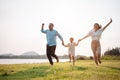 Happy family in the park sunset light. family on weekend running together in the meadow with river Parents hold the child hands. Royalty Free Stock Photo