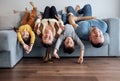 Happy family people and their kids in casual clothes are lying upside down on their backs on grey sofa Royalty Free Stock Photo