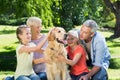 Happy family petting their dog in the park Royalty Free Stock Photo