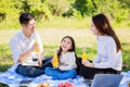 Happy family picnic. Asian parents Father, Mother and little girl drinking orange juice and have fun and enjoyed ourselves toget Royalty Free Stock Photo