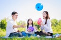 Happy family picnic. Asian parents Father, Mother and little girl playing balloon and have enjoyed ourselves together