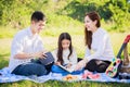 Happy family picnic. Asian parents Father, Mother and little girl reading a book and have fun and enjoyed ourselves together Royalty Free Stock Photo