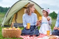 Happy family on picnic at camping. Mother and daughter eating near a tent in meadow or park Royalty Free Stock Photo