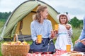 Happy family on picnic at camping. Mother and daughter eating near a tent in meadow or park Royalty Free Stock Photo