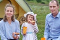 Happy family on picnic at camping. Mother, father and daughter eating near a tent in meadow or park Royalty Free Stock Photo