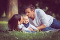 A happy family on a picnic. Infant, mother and father in outside in nature. Both parents kissing the boy