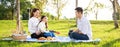 Happy family picnic. A little girl playing ukulele with her parents Father, Mother during picnicking on a picnic cloth on a Royalty Free Stock Photo