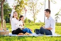 Happy family picnic. A little girl playing ukulele with her parents Father, Mother during picnicking on a picnic cloth on a Royalty Free Stock Photo