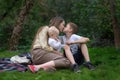 Happy family at picnic. Young mother kisses her older son and holding baby