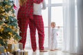 Happy family in plaid pajamas near the big window in the living room with a Christmas tree. Mother, father and little son waiting Royalty Free Stock Photo