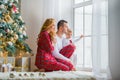 Happy family in plaid pajamas near the window in the living room with a Christmas tree. Mother, father and little son waiting for Royalty Free Stock Photo