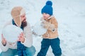 Happy family plaing with a snowman on a snowy winter walk. Father and son making snowball on winter white background.