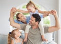 Happy family, play and bonding on a sofa in their home, cheerful and having fun. Young parents being playful and loving