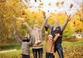 Happy family playing with autumn leaves in park