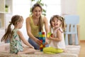 Happy family playing with cubes on the floor. Mother and daughters spend fun time together. Royalty Free Stock Photo