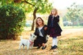 Happy family playing with dog in autumn park. Mother and daughter having fun together on a walk Royalty Free Stock Photo