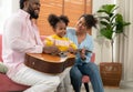 Happy family playing guitar together on the couch in living room at home Royalty Free Stock Photo