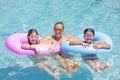 Happy Family playing on inflatable tubes in a swimming pool on a sunny day Royalty Free Stock Photo