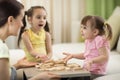 Happy family playing jenga together at home. Mother and daughters having fun in living room.