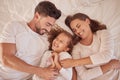 Happy family playing and laughing together on the bed having fun at home on a weekend. Playful and carefree parents Royalty Free Stock Photo
