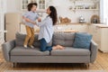 Mother and child laughing having fun, holding hands and jumping on sofa at home. Happy family. Royalty Free Stock Photo