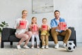 happy family with popcorn boxes sitting on sofa and smiling