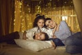 Affectionate mother and two little daughter relaxing in tent in home living room