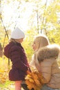 Happy family portrait, blonde mother and daughter look each other in autumn forest Royalty Free Stock Photo