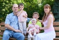 Happy family portrait on outdoor, group of five people sit on wooden bench in city park, summer season, child and parent Royalty Free Stock Photo