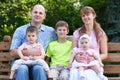 Happy family portrait on outdoor, group of five people sit on wooden bench in city park, summer season, child and parent Royalty Free Stock Photo