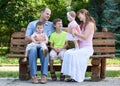 Happy family portrait on outdoor, group of five people sit on wooden bench in city park, summer season, child and parent Royalty Free Stock Photo