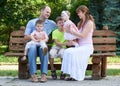 Happy family portrait on outdoor, group of five people sit on wooden bench in city park, summer season, child and parent Royalty Free Stock Photo