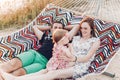 Happy family portrait, young hipster father and mother lying in a hammock with their baby daughter, summer vacation family trip Royalty Free Stock Photo