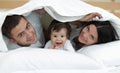 Happy family posing under a duvet while looking at the camera Royalty Free Stock Photo