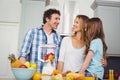 Happy family preparing fruit juice at table