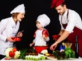 Happy family preparing healthy food together in kitchen. Adorable son in chef hat with parents cooking together at home Royalty Free Stock Photo