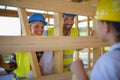 Happy family in protective clothes checking their unfinished eco wooden house, concept of sustainability and healthy Royalty Free Stock Photo