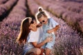 Happy family in purple lavender field. young beautiful mother and child Girl enjoy walking blooming meadow on summer day Royalty Free Stock Photo