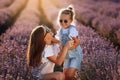 Happy family in purple lavender field. young beautiful mother and child Girl enjoy walking blooming meadow on summer day Royalty Free Stock Photo