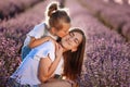 Happy family in purple lavender field. young beautiful mother and child Girl enjoy walking blooming meadow on summer day Royalty Free Stock Photo