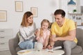 Happy family putting coin into piggy bank at table. Saving money Royalty Free Stock Photo