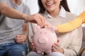 Happy family putting coins into piggy bank at home, closeup Royalty Free Stock Photo