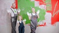 Happy family are putting their white handprints on a green wall - looking in the camera