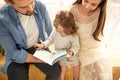 Happy family reading a book to her daughter. Royalty Free Stock Photo