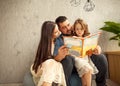 Happy family reading a book to her daughter. Mothers Day. Royalty Free Stock Photo