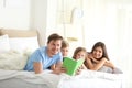 Happy family reading book together in bedroom Royalty Free Stock Photo